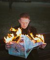 a young boy burning a newspaper