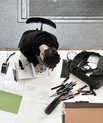 Young man working on desk with lots of pens and paper around him taken from above.