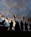 Dark hillside with men in Viking costume with torches